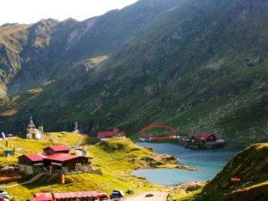 On the shore of Balea lake, there are a few tents in the middle of the image, right above the parking cars